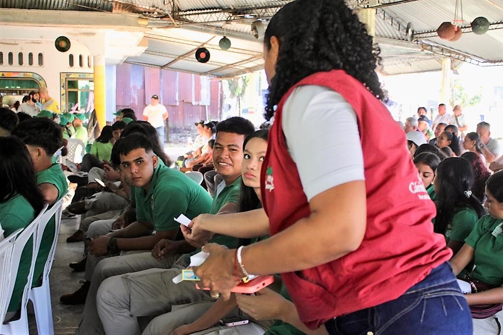 Ansatt i Caritas Colombia deler ut stemmesedler til ungdom på lokalt valgkampmøte