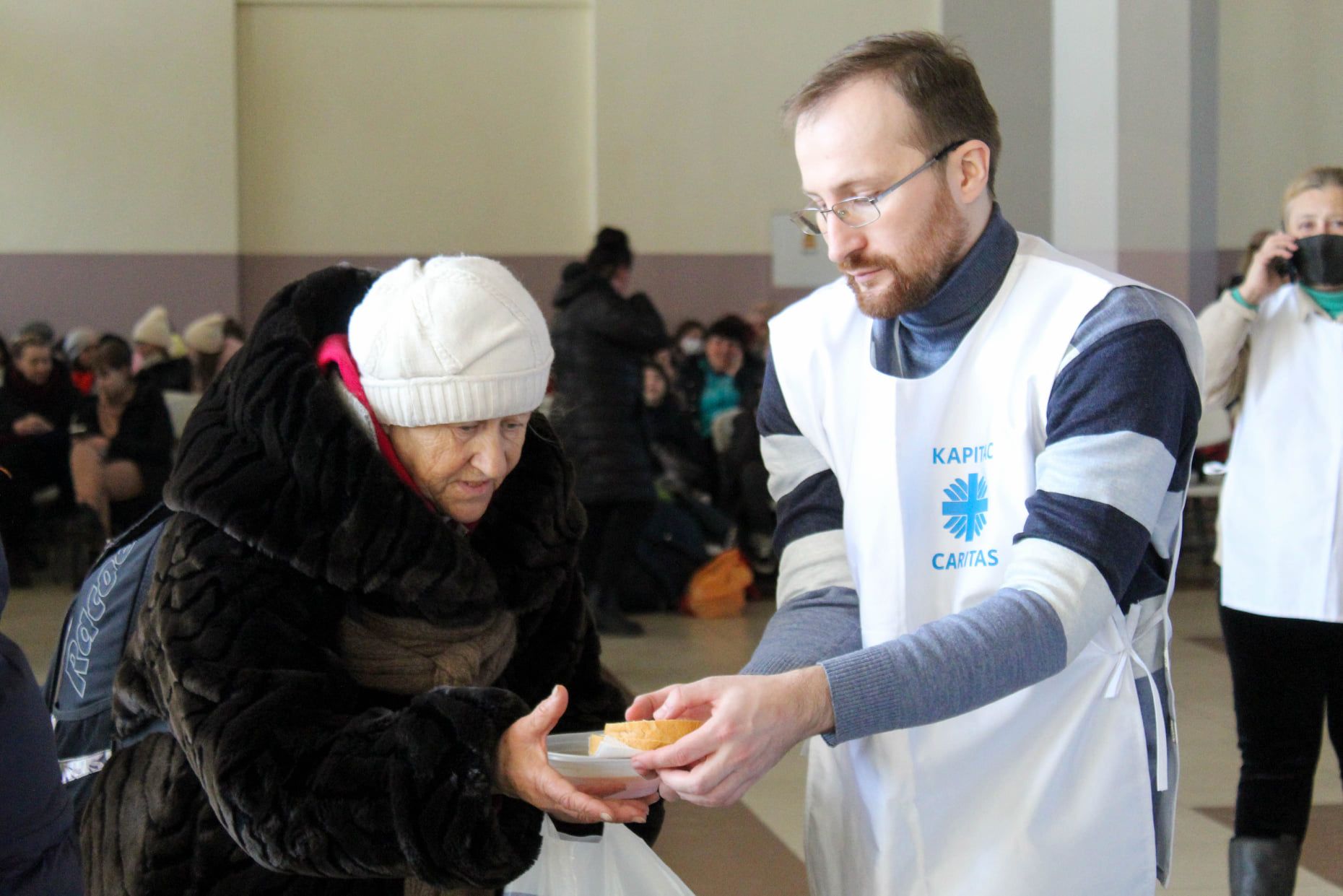 Eldre dame får utdelt brødskiver av en frivillig i Caritas Ukraina.