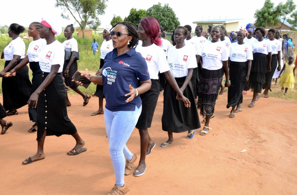 En gruppe unge flyktningkvinner i Uganda feirer at de har gjennomført lese- og skriveopplæring.