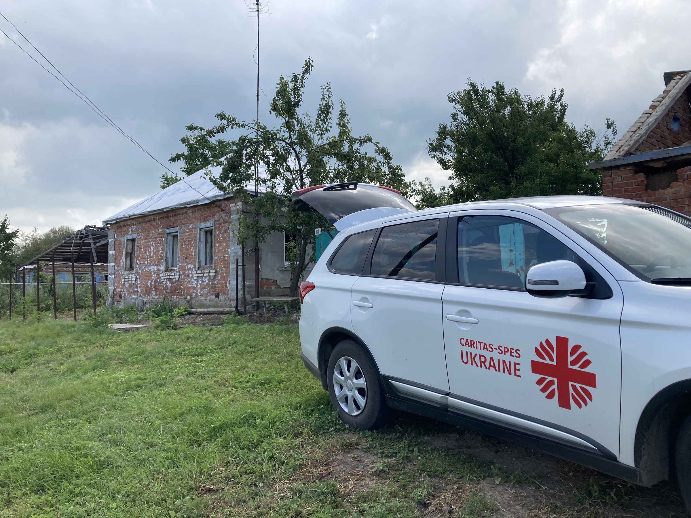Bilen til Caritas Spes står utenfor hus i en av landsbyene utenfor Kharkiv