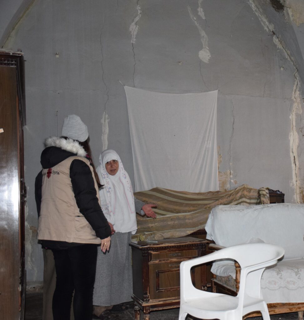 En Caritas-ansatt i Syria snakker med en kvinne som får hjelp til gjenoppbygging av hjemmet.